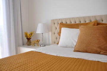 quarto cama arrumada com almofadas amarelas e brancas 