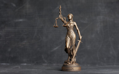 themis is goddess of justice statuette on dark background. symbol of law with scales and sword in...