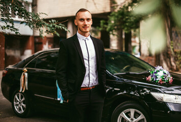 Confident wealthy elegant man in suit near classic car