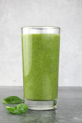 Spinach green detox smoothie in glass on gray background.