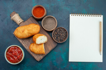 top view delicious pies with meat filling notepad and seasonings on the dark blue background dough pie bread bun food bake