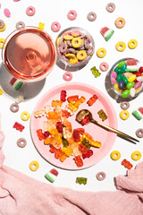 Plate with gummy bears, jelly beans and a glass with pink drink