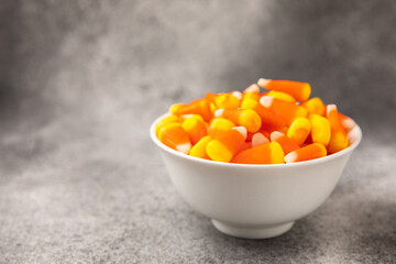 Halloween candy corn with pumpkin flavor and dragees on a black background. Classic sweet Halloween treats. Halloween holiday concept and Jack lantern.Place for text. Place to copy.