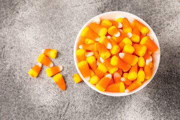Halloween candy corn with pumpkin flavor and dragees on a black background. Classic sweet Halloween treats. Halloween holiday concept and Jack lantern.Place for text. Place to copy.