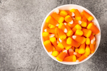 Halloween candy corn with pumpkin flavor and dragees on a black background. Classic sweet Halloween treats. Halloween holiday concept and Jack lantern.Place for text. Place to copy.
