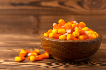 Halloween candy corn with pumpkin flavor and dragees on a brown background. Classic sweet Halloween treats. Halloween holiday concept and Jack lantern.Place for text. Place to copy.