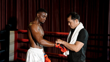 Mentor putting on gloves for African athletic man preparing for boxing By wearing sportswear, wearing pants, not wearing a shirt. man with strong muscles