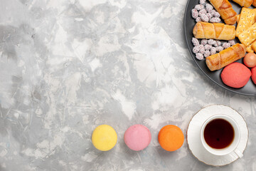 top view delicious sweet bagels with crackers french macarons and cup of tea on light white desk biscuit cookie sugar sweet pie