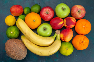 top view different fruit composition bananas tangerines apples on dark-blue desk fruit fresh mellow ripe color vitamine - obrazy, fototapety, plakaty