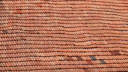 A wavy roof with old tiles. Everything in good condition. Orange background