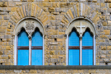 Fototapeta na wymiar Facade of medieval building with traditional windows in Florence city, Tuscany, Italy. Сlose-up with details