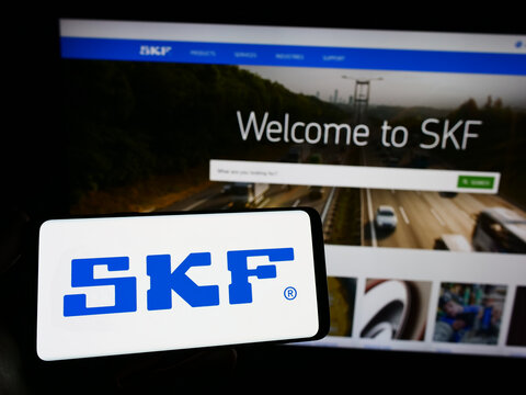 Stuttgart, Germany - 04-28-2023: Person holding smartphone with logo of Swedish bearing manufacturing company SKF AB on screen in front of website. Focus on phone display.