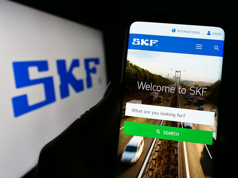 Stuttgart, Germany - 04-28-2023: Person holding cellphone with webpage of Swedish bearing manufacturing company SKF AB on screen with logo. Focus on center of phone display.