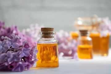 Cosmetic oil, lilac flower on a light background