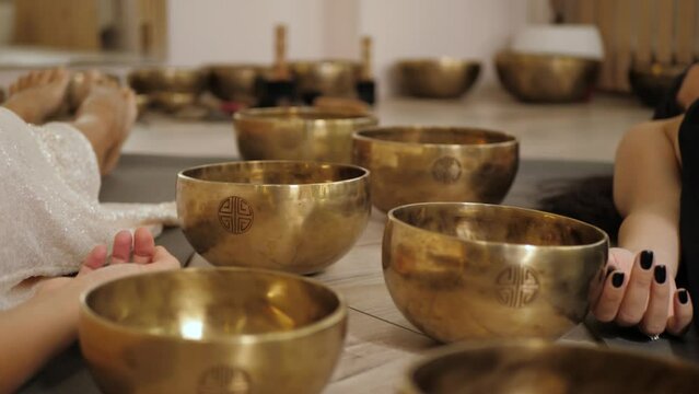 Singing bowls, lying two unrecognizable women in white and black having a relaxing sound therapy