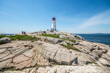 Lighthouse by sea against sky in Peggy's Cove, Nova Scotia. - obrazy, fototapety, plakaty