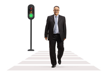 Full length portrait of a mature businessman smiling and walking at pedestrian crossing