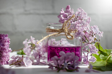 Obraz na płótnie Canvas Cosmetic oil, lilac flower on a light background