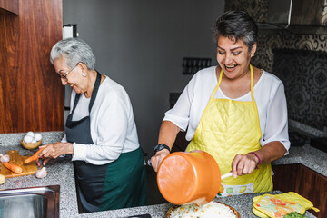 latin women grandmother and daughter cooking at home kitchen in Mexico Latin America, hispanic...
