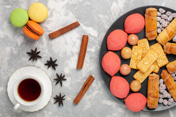 top view yummy cakes with candies crackers macarons and cup of tea on the white background cake biscuit cookies sugar sweet pie
