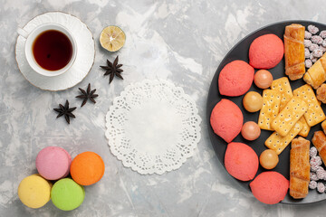 top view yummy cakes with candies crackers macarons and cup of tea on white background cake biscuit cookies sugar sweet pie