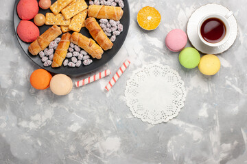 top view yummy cakes with crackers french macarons and cup of tea on grey-white desk cake biscuit cookies sugar sweet pie