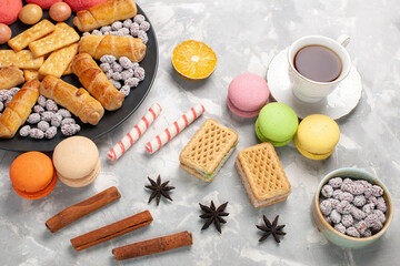 top view yummy cakes with crackers french macarons waffles and cup of tea on grey white desk cake biscuit cookies sugar sweet pie