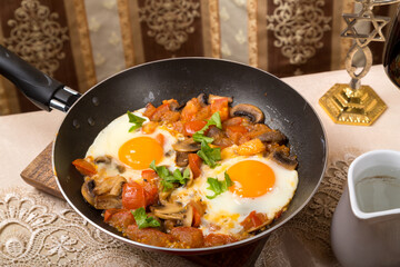 A set table and hot shakshuka in a frying pan.