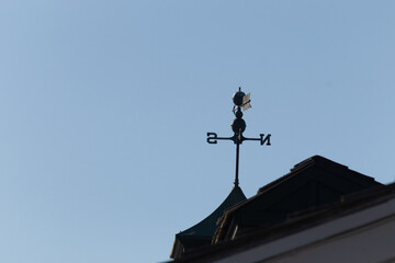 Fototapeta na wymiar This weather vane was beautiful on the roof contrasted against the sky. The shadowy image with the clear blue sky in the background. The North, South, East, and West showing direction of the wind.