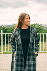Obraz premium Vertical portrait of a young blonde woman wearing coat on a windy day outdoors.