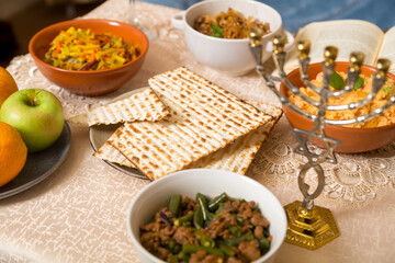 Shabbat set table with couscous, vegetables with meat, fruit, matzah and menorah.