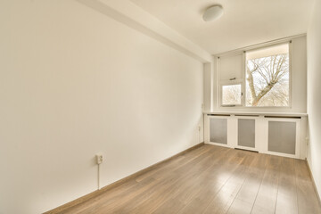 an empty room with wood flooring and white paint on the walls there is a small window in the corner