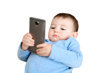 Doubting toddler baby boy is sitting with a phone on the sofa in the living room, isolated on a white background. Child with a smartphone in his hands on the bed