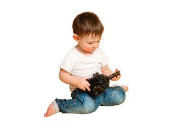 Toddler baby photographer with a camera on a studio isolated on a white background. Happy child with photo equipment in a white t-shirt and blue jeans, copy space. Kid aged one year and four months