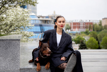 young girl in a suit with a brown doberman on a city street