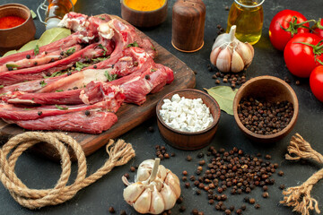 front view raw meat slice with fresh vegetables and seasonings on a dark gray background salad raw meat dish meal butcher