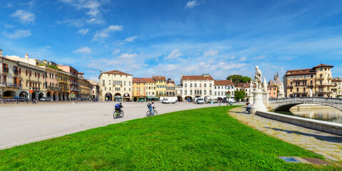 Fototapeta na wymiar Cyclists in the square Prato della Valle in Padova (Padua), Veneto region, Italy. Cycling tourism. Sunny day, beautiful sky, soft light. Travel destination concept