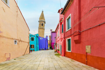 Fototapeta na wymiar Colorful houses on Burano island, Venice Italy. In the background is the falling bell tower of the Roman Catholic Church of Bishop St. Martin