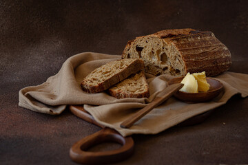 Loaf of sourdough bread on wooden board on dark grey background 