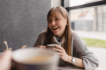 White women smiling and talking while drinking tea in cafe indoors. Girls have good conversation,...
