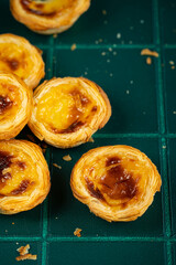 Group of traditional Portuguese pastel de nata on green tiled surface.
