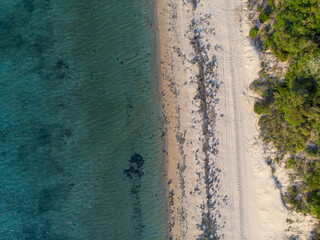 Leerer Strand mit weißen Sand und einigen Steinen und Felsen in Mosambik, Afrika, fotografiert aus der Luft mit einer Drohne bei einem Rundflug