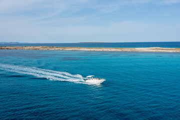 A yacht gliding through the beautiful blue waters of Formentera, with a couple on board enjoying the motion