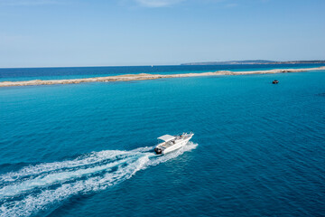A yacht gliding through the beautiful blue waters of Formentera, with a couple on board enjoying the motion