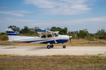 Ein Propellerflugzeug Cessna rollt über eine Schotterpiste / Airstrip im Okavango Delta in Botswana, Afrika