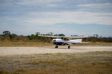 Propellerflugzeug Cessna startet auf einer Schotterpiste / Airstrip im Okavango Delta in Botswana, Afrika	