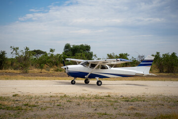 Propellerflugzeug Cessna rollt über eine sandige Schotterpiste / Airstrip im Okavango Delta in...