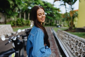 Portrait of a woman brunette smile with teeth walking outside against a backdrop of palm trees in the tropics, summer vacations and outdoor recreation, the carefree lifestyle of a freelance student.