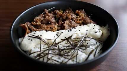 Gyu cheese don consist of Juicy beef, sautéed and served over rice with a savory, creamy cheese sauce and some seaweed topping.