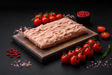 Fresh minced chicken with salt, spices and herbs on a wooden cutting board